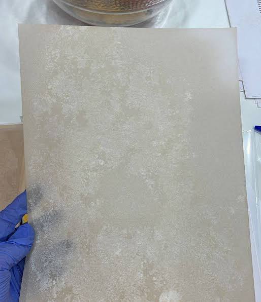 A stack of high-purity, infused K2 paper sheets resting beside an analytical testing sheet on a clean table.