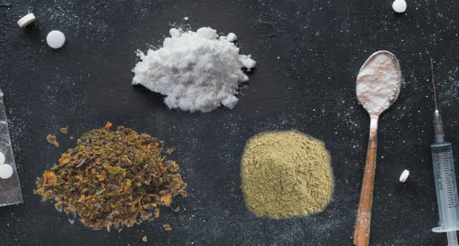 A sealed pouch of premium K2 spice herbal incense resting beside an analytical testing sheet on a clean table.